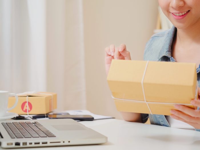 Beautiful smart Asian young entrepreneur business woman owner of SME online checking product on stock and save to computer working at home. Small business owner at home office concept.